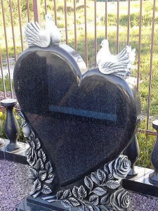 Резной памятник в виде сердца с двумя голубями