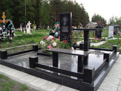 Памятник с черного гранитной оградой, лавочкой и столом